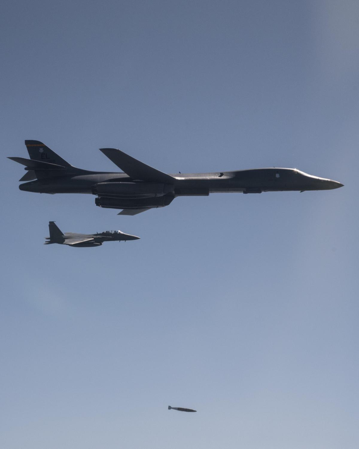 A U.S. Air Force B-1B Lancer bomber, flanked by South Korean F-15K Slam Eagle fighters, drops a 2,000-pound live munition at Pilsung Training Range, South Korea, as a part of a show of force mission in response to North Korean unsanctioned intercontinental ballistic missile tests, Sept. 17, 2017. (Air Force photo by Capt. Mike Karnes)
