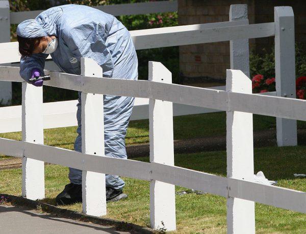 A police forensic investigator searches for fingerprints on a fence of a front garden near the scene of the murder of 16-year-old Shakilus Townsend at Thornton Heath on July 4, 2008, in Croydon, south London, England. (Daniel Berehulak/Getty Images)