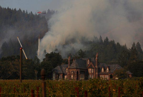 A firefighting helicopter drops water to defend a vineyard from an approaching wildfire in Santa Rosa, Calif., on Oct. 14, 2017. (Reuters/Jim Urquhart)