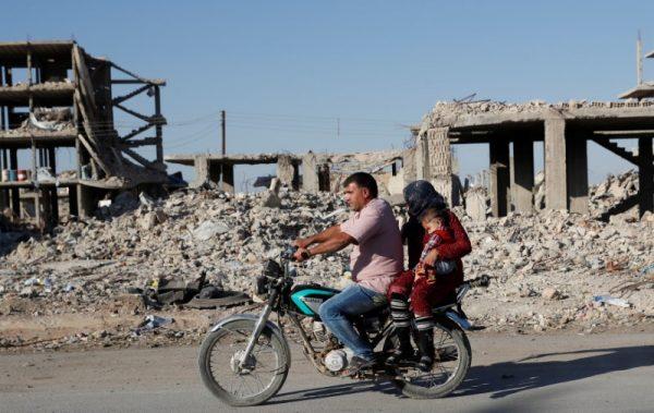 Motorists ride a motorcycle past ruins of buildings destroyed during fightings with the ISIS terrorists in Kobani, Syria October 11, 2017. (Reuters/Erik De Castro)