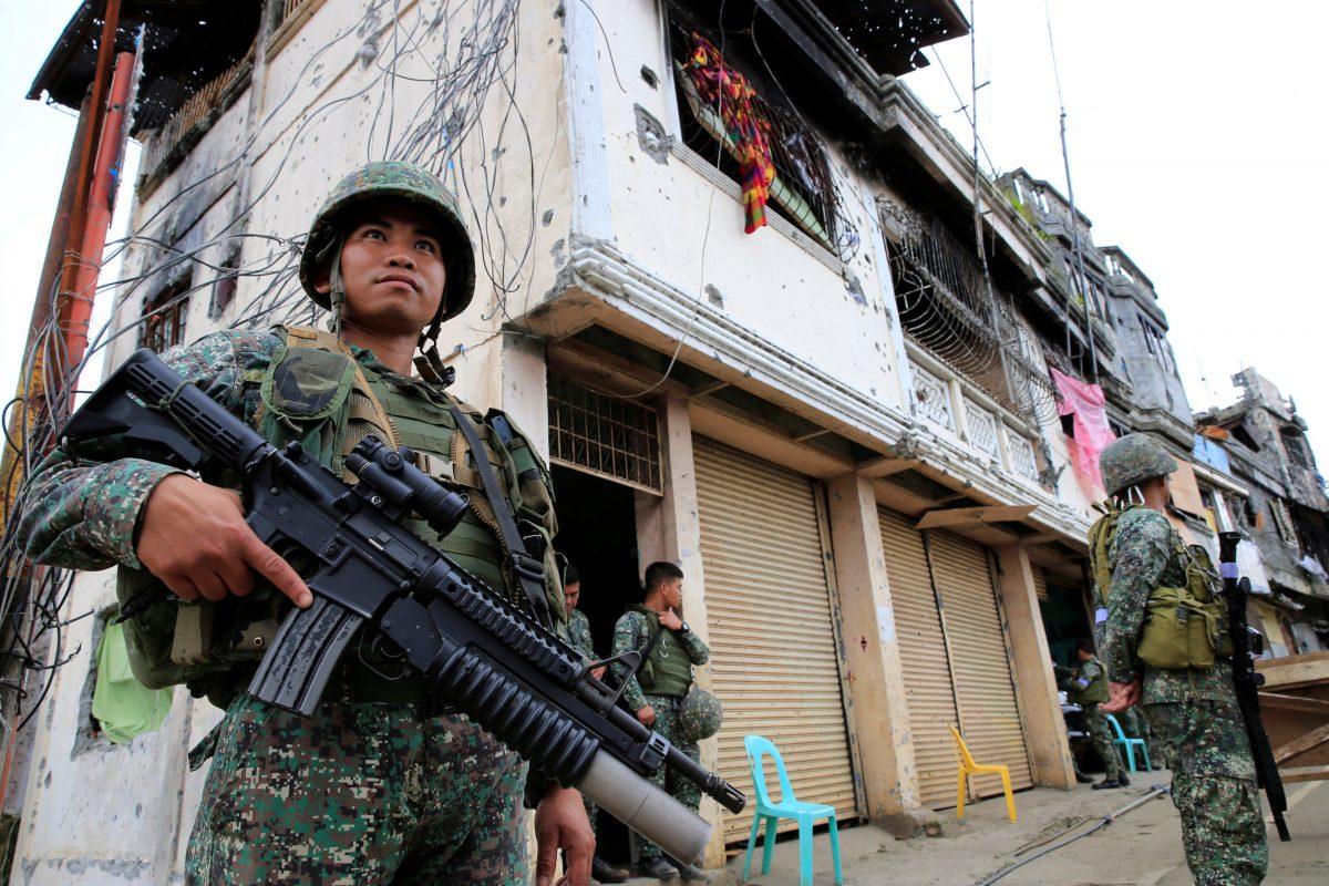 Government soldiers stand guard in front of damaged building and houses in Sultan Omar Dianalan boulevard at Mapandi district in Marawi city, southern Philippines, Sept. 13, 2017. (Reuters/Romeo Ranoco)