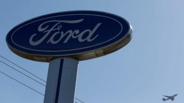 An airplane flies above a Ford logo in Colma, Calif., on Oct. 3, 2017. (Stephen Lam/Reuters)