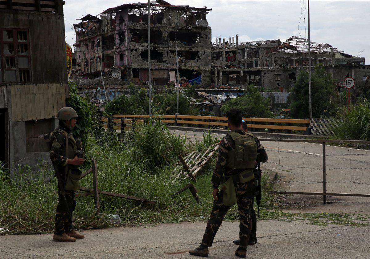 Soldiers stand on guard and look at damaged buildings and houses after government troops cleared the area from pro-ISIS terrorist groups inside the war-torn area in Saduc proper, Marawi city, southern Philippines on Oct. 22, 2017. (REUTERS/Romeo Ranoco)
