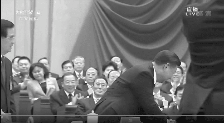 Xi appears to be shaking hands with Jiang, but the view is blocked by a cameraman. (Screenshot via YouTube/CCTV)