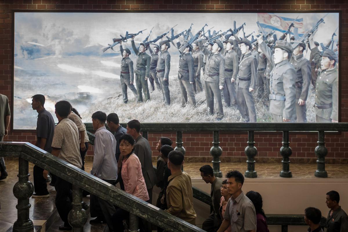 People walk up stairs before a propaganda poster showing Korean People's Army (KPA) soldiers at a museum in Sinchon, south of Pyongyang on July 29, 2017. North Korea said July 30 its latest ICBM test was a "warning" targeting the United States for its efforts to slap new sanctions on Pyongyang and threatened a counter-strike if provoked militarily by Washington. (ED JONES/AFP/Getty Images)