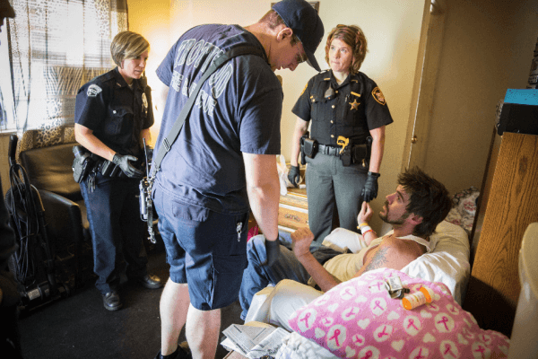 Law enforcement and emergency personnel assist a man who is experiencing a drug overdose in the Drexel neighborhood of Dayton, Ohio, on Aug. 3, 2017. (Benjamin Chasteen/The Epoch Times)