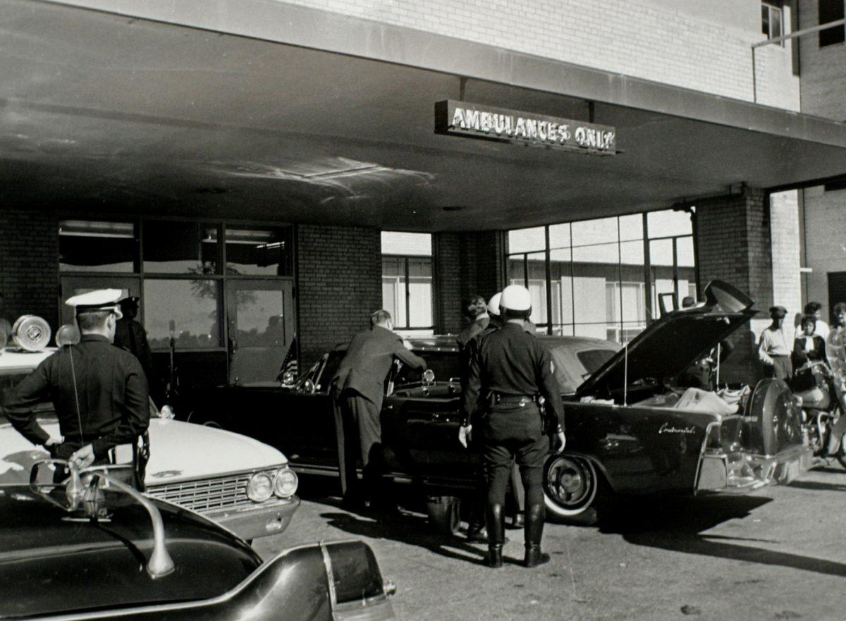 U.S. Secret Service agents and local police examine the presidential limousine as it sits parked at Parkland Memorial Hospital in Dallas, Texas under a sign reading "Ambulances Only" as President John F. Kennedy is treated inside the hospital after being shot while driving through the streets of Dallas on Nov. 22, 1963. (JFK Library/Cecil Stoughton/The White House/Handout/File Photo via REUTERS)