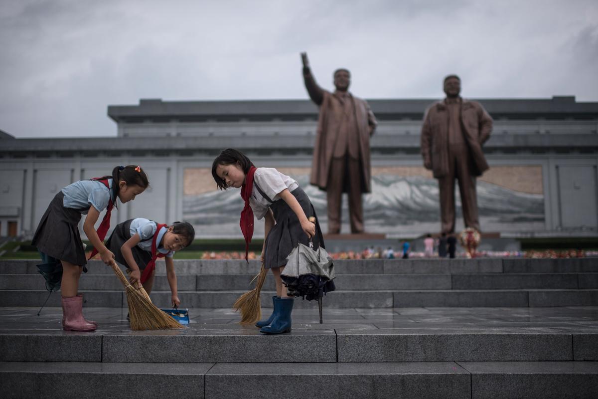 Students clean the steps in front of the statues of late North Korean leaders Kim Il-Sung and Kim Jong-Il at Mansu Hill as the country marks 'Victory Day' in Pyongyang on July 27, 2017. (ED JONES/AFP/Getty Images)