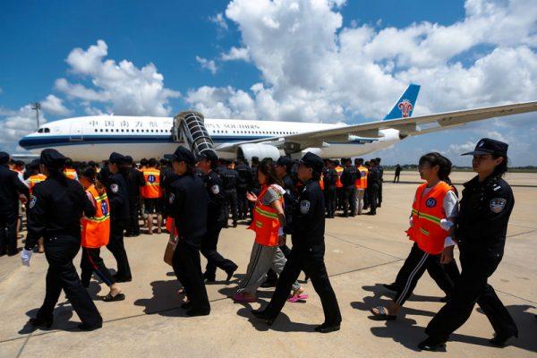 Chinese nationals (in orange vests) who were arrested over a suspected internet scam, are escorted by Chinese police officers before they were deported at Phnom Penh International Airport, in Phnom Penh, Cambodia, October 12, 2017. (Reuters/Samrang Pring)