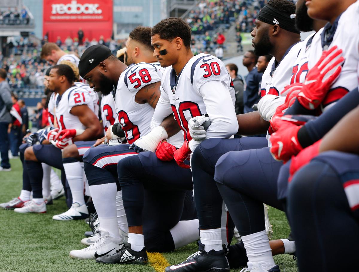 Members of the Houston Texans, including Kevin Johnson #30 and Lamarr Houston #58, kneel during the national anthem before the game at CenturyLink Field on October 29. (Photo by Jonathan Ferrey/Getty Images)