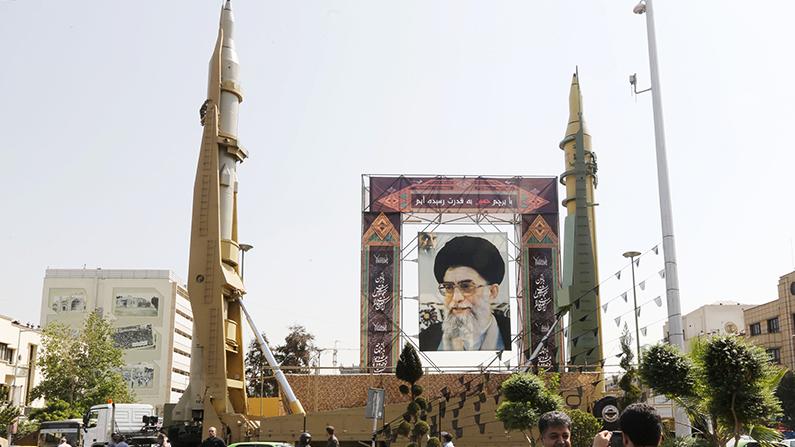 Iranians walk past Sejjil (L) and Qadr-H medium-range ballistic missiles displayed next to a portrait of Iranian Supreme Leader Ayatollah Ali Khamenei on Sept. 25, 2017, on Baharestan square in Tehran. (Atta Kenare/AFP/Getty Images)
