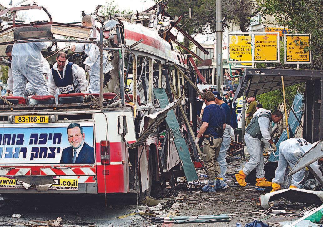 Forensic officers and Israeli police examine a bus after a Palestinian suicide bombing in Haifa, Israel, on March 5, 2005. (DAVID SILVERMAN/GETTY IMAGES)