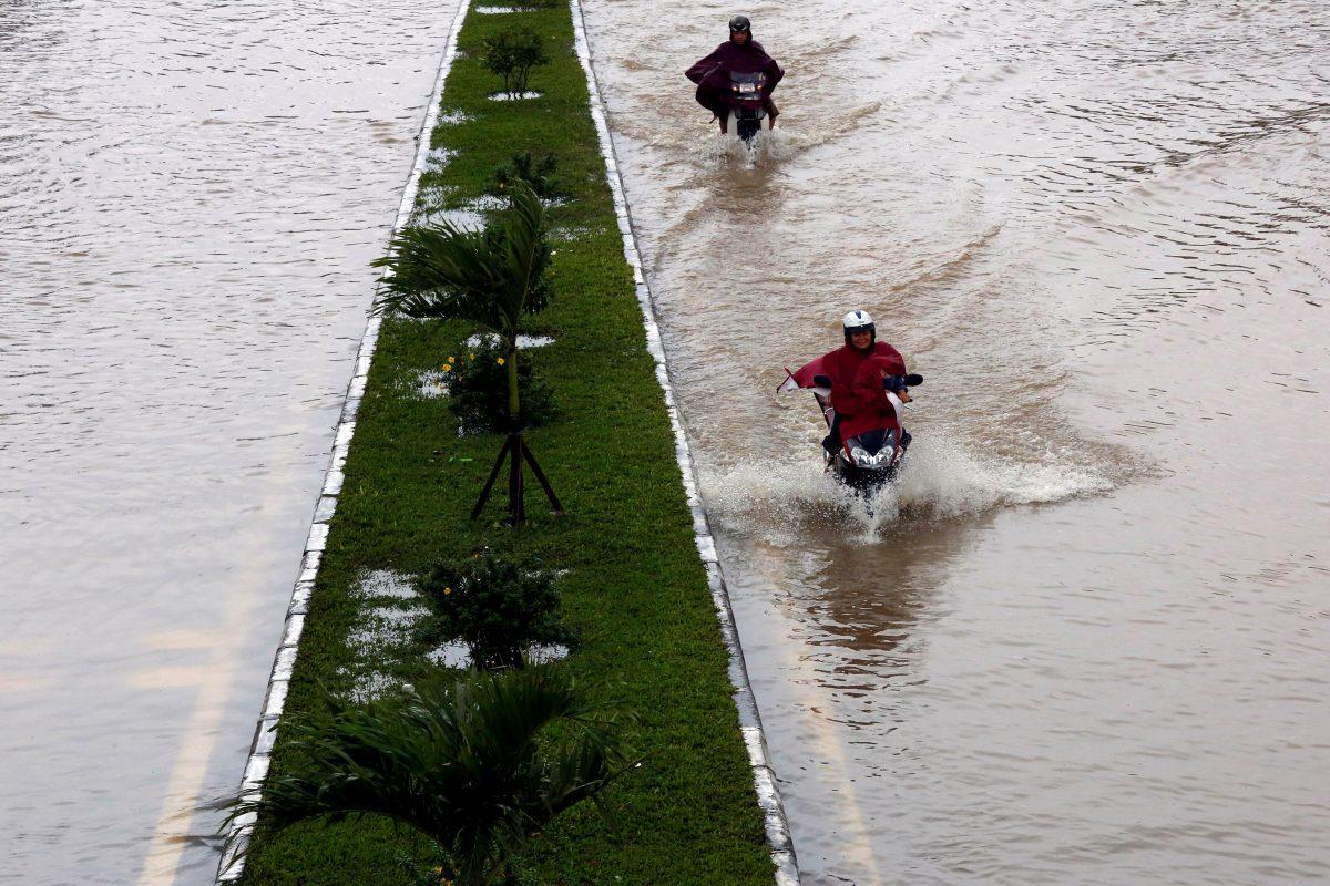 People ride motorcycles along flooded road after typhoon Damrey hits Vietnam in Hue city, Vietnam Nov. 5, 2017. (REUTERS/Kham)