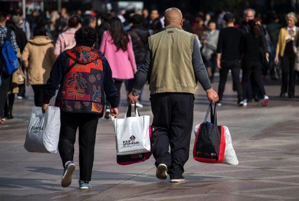 A couple carries shopping bags on the main shopping street at West Nanjing Road, during the Nov. 11 shopping festival in Shanghai on November 11, 2016. (Johannes Eisele/AFP/Getty Images)