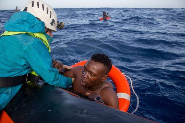A member of German NGO Sea-Watch (L) helps a migrant to board a boat after he was recovered in the Mediterranean Sea on Nov. 6, 2017. (Alessio Paduano/AFP/Getty Images)
