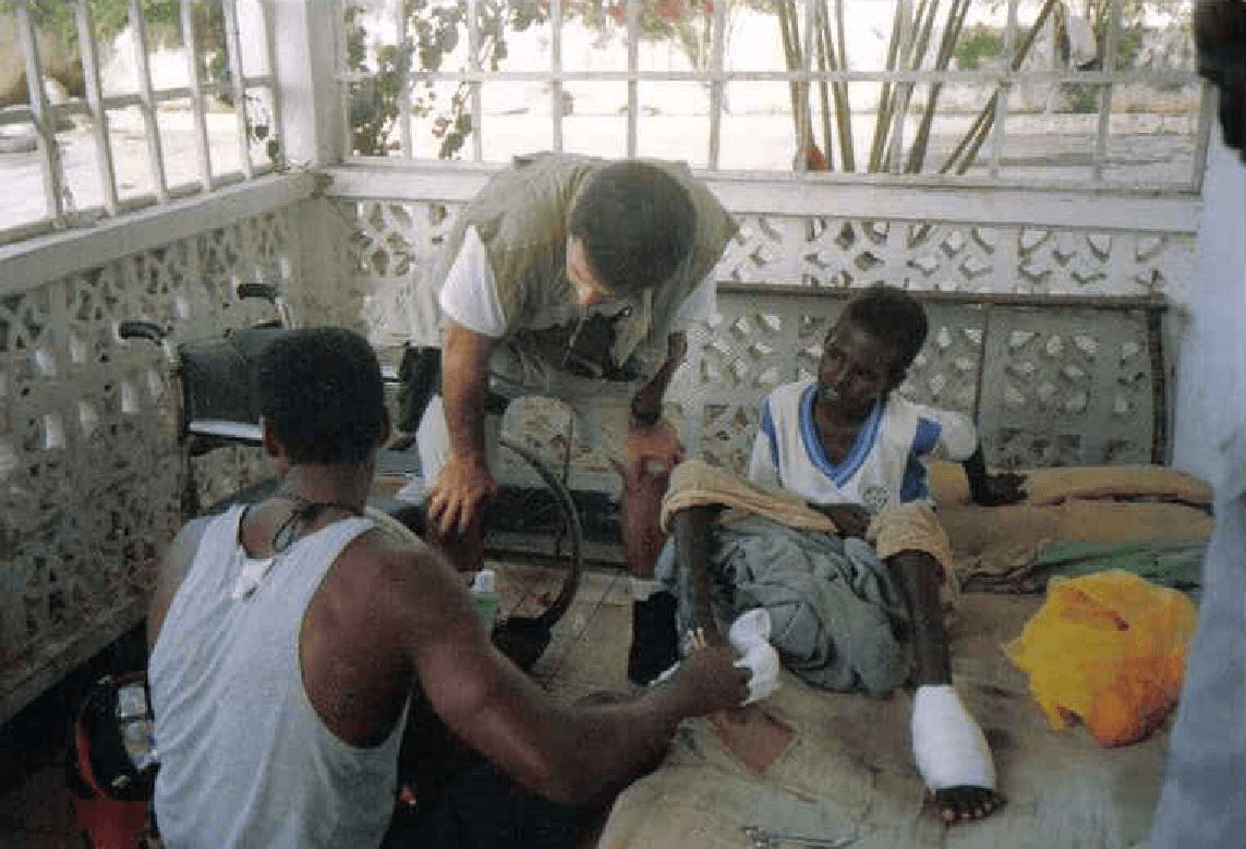 Members of Howard Wasdin's team in Mogadishu treat a young boy who was injured by an enemy landmine in 1993. (Courtesy of Howard Wasdin)
