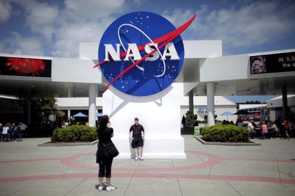 Tourists take pictures of a NASA sign at the Kennedy Space Center visitors complex in Cape Canaveral, Fla., on April 14, 2010. (REUTERS/Carlos Barria)