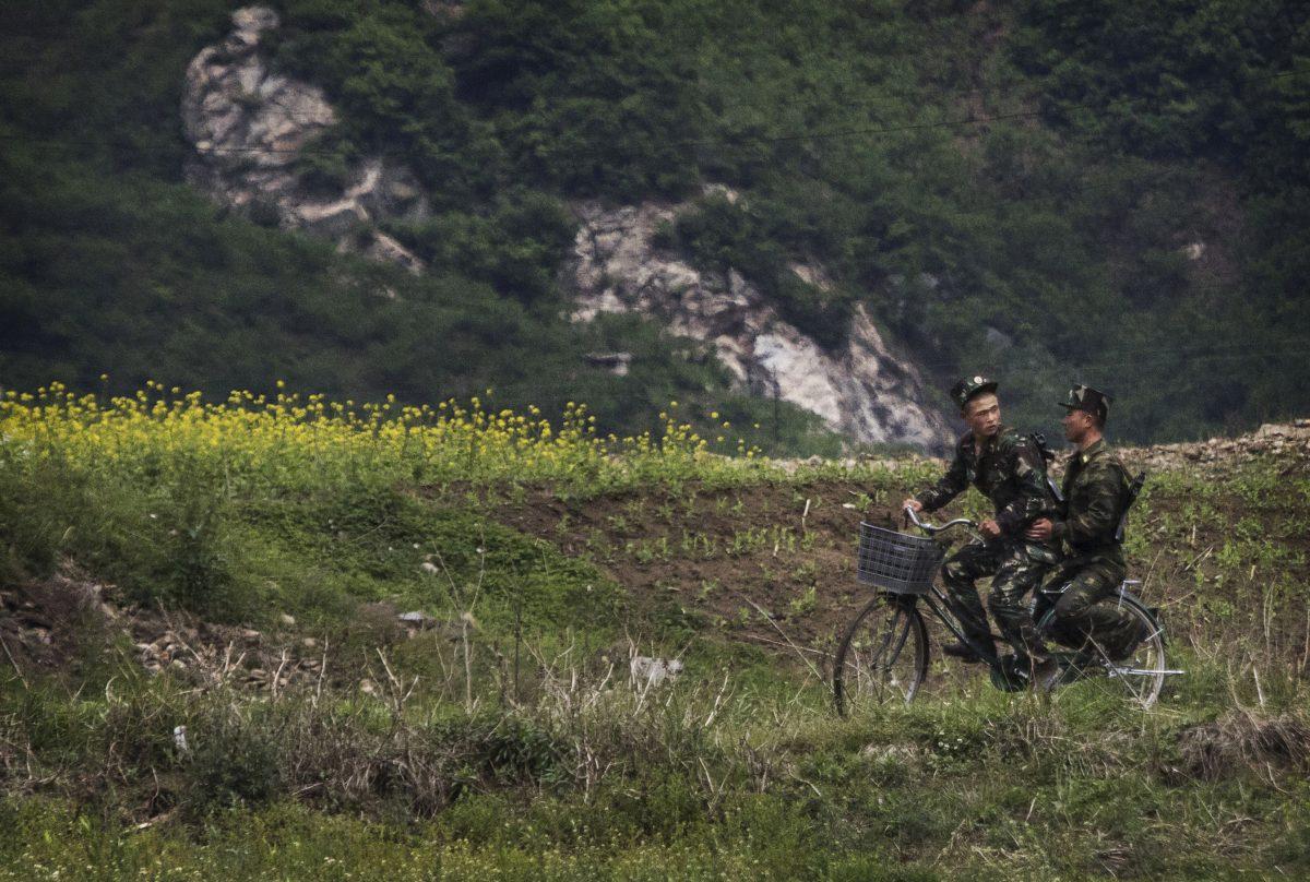 North Korean soldiers ride on a bicycle on the Yalu River north of the border city of Sinuiju, North Korea on May 23, 2017. (Kevin Frayer/Getty Images)