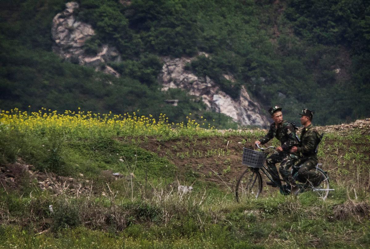 North Korean soldiers ride on a bicycle on the Yalu river north of the border city of Sinuiju, North Korea, on May 23, 2017. (Kevin Frayer/Getty Images)