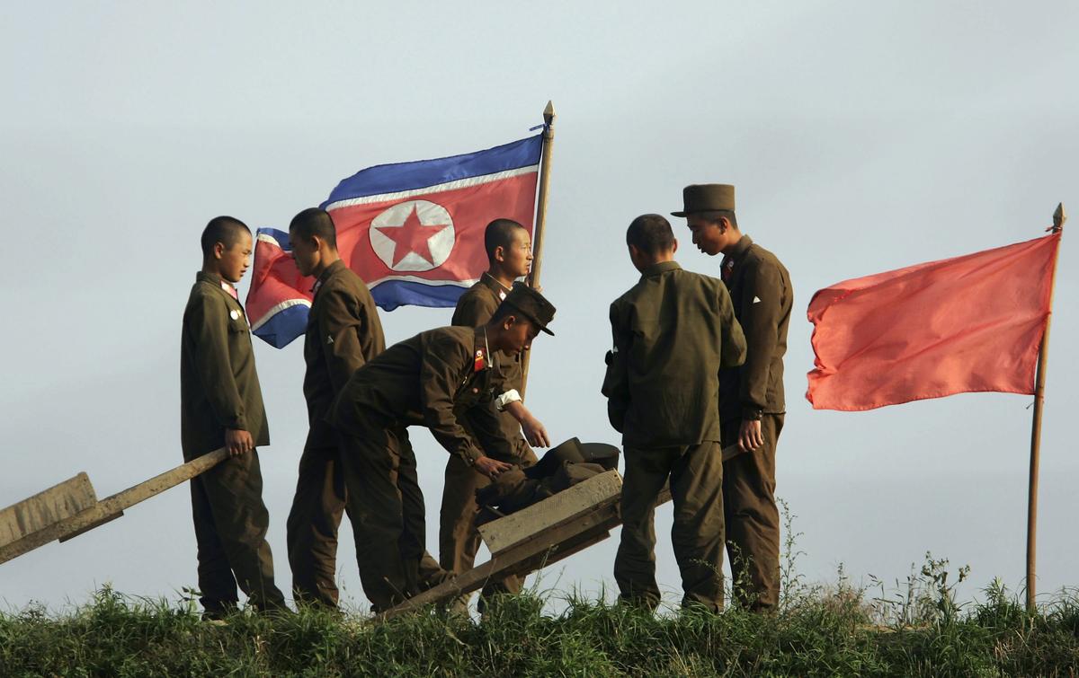 Korean soldiers work at the farmland near a North Korean flag on the outskirts of the North Korean city of Sinuiju in this picture taken on October 18, 2006. (Photo by Cancan Chu/Getty Images)