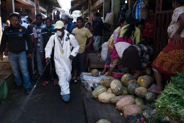 People stand back as a council worker sprays disinfectant during the cleanup of the market of Anosibe in the Anosibe district, one of the most insalubrious districts of Antananarivo, Madagascar, on Oct. 10, 2017. (RIJASOLO/AFP/Getty Images)