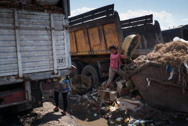 A girl empties a basket of garbage into a full dumpster as Council workers begin to clear garbage during the clean-up of the market of Anosibe in the Anosibe district, one of the most insalubrious districts of Antananarivo, Madagascar, on Oct. 10, 2017. (RIJASOLO/AFP/Getty Images)