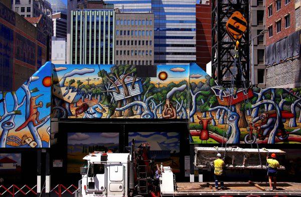 Workers guide a large metal girder as it is lowered by a crane on a construction site for a new building decorated with artwork in Sydney's central business district, Australia, on Nov. 9, 2017. (REUTERS/David Gray)