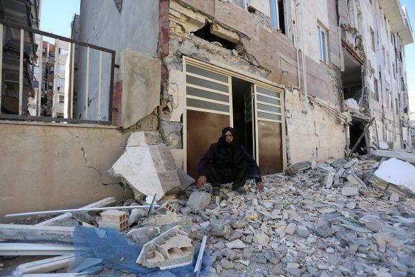 A man sits outside a damaged belonging following an earthquake in Sarpol-e Zahab county in Kermanshah, Iran November 13, 2017. (REUTERS/Tasnim News Agency)