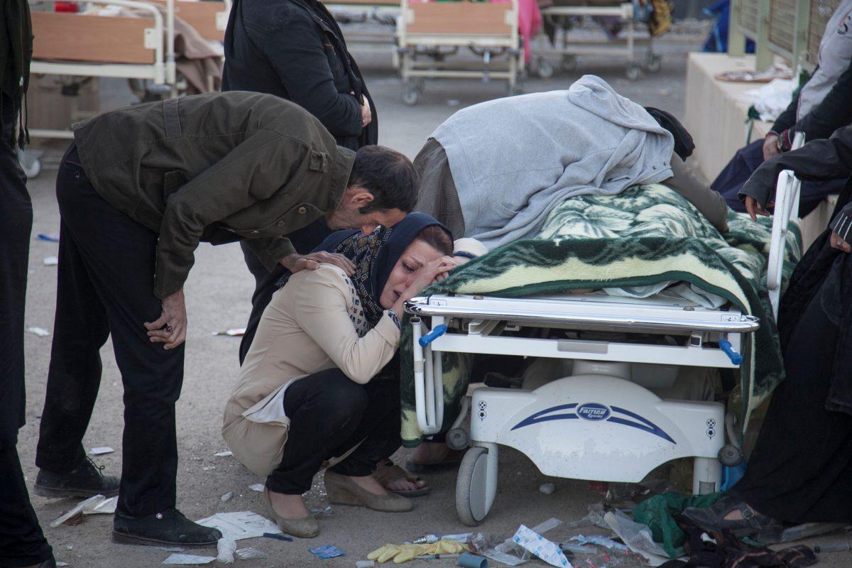 A woman reacts next to a dead body following an earthquake in Sarpol-e Zahab county in Kermanshah, Iran. (REUTERS/Tasnim News Agency)