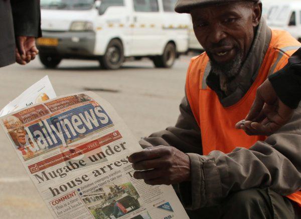 A street vendor reads a newspaper in central Harare, Zimbabwe, Nov. 16, 2017. (Reuters/Philimon Bulawayo)