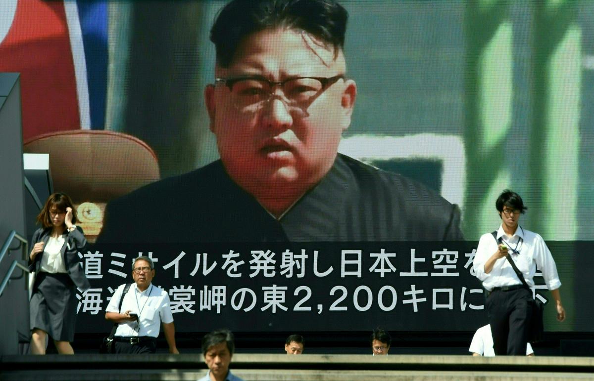 Pedestrians walk in front of a large video screen in Tokyo broadcasting a news report showing North Korean leader Kim Jong-Un, following a North Korean missile test that passed over Japan on September 15, 2017.<br/> (TORU YAMANAKA/AFP/Getty Images)