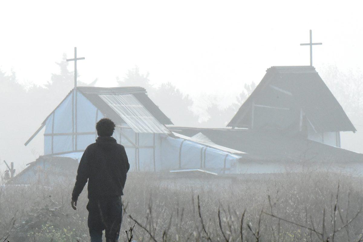 A migrant walks past a makeshift church in the "Jungle" migrant camp in Calais, northern France, on Oct. 23, 2016. (FRANCOIS LO PRESTI/AFP/Getty Images)