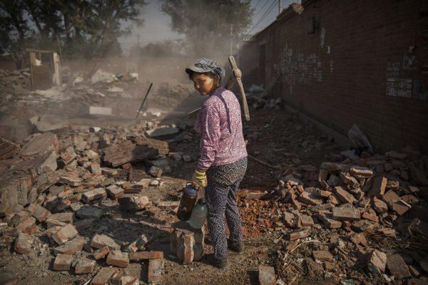 A Chinese laborer waits to assist in demolishing a home in Gucheng Village, Tongzhou District, Beijing, on October 15, 2015. (Photo by Kevin Frayer/Getty Images)