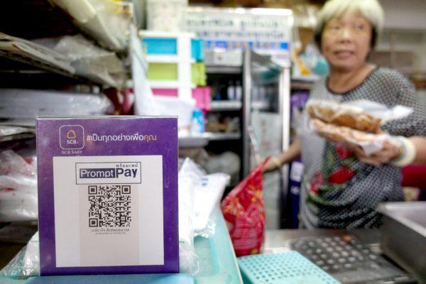 An advertisement board displaying a QR code is seen as a vendor works at a market in Bangkok, Thailand, November 22, 2017. (Reuters/Athit Perawongmetha)
