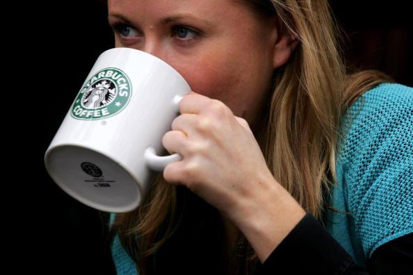 A woman drinks from a coffee mug in A Starbucks store in central London.(Daniel Berehulak/Getty Images)