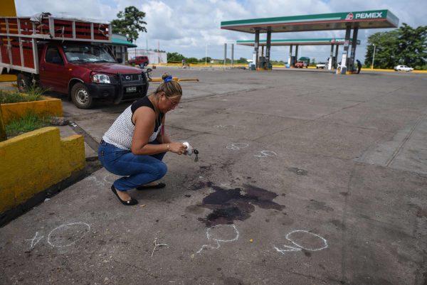 A relative places a candle beside the pool of dry blood that remains on the place where Mexican journalist Candido Rios was killed in front of a petrol station in Hueyapan de Ocampo, Veracruz state, Mexico on Aug. 23, 2017. (Victoria Razo/AFP/Getty Images)
