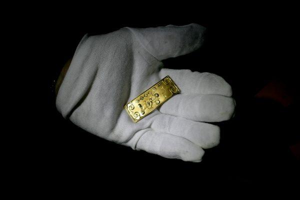 A craftsman displays a gold bar etched with a rat pattern, at a workshop in Chongqing City, China, on February 2, 2008. (China Photos/Getty Images)