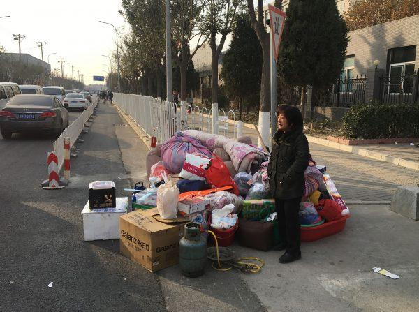 A resident stands next to her belongings after being evacuated from the housing block fire in Beijing on Nov. 19, 2017. (Ryan Mcmorrow/AFP/Getty Images)