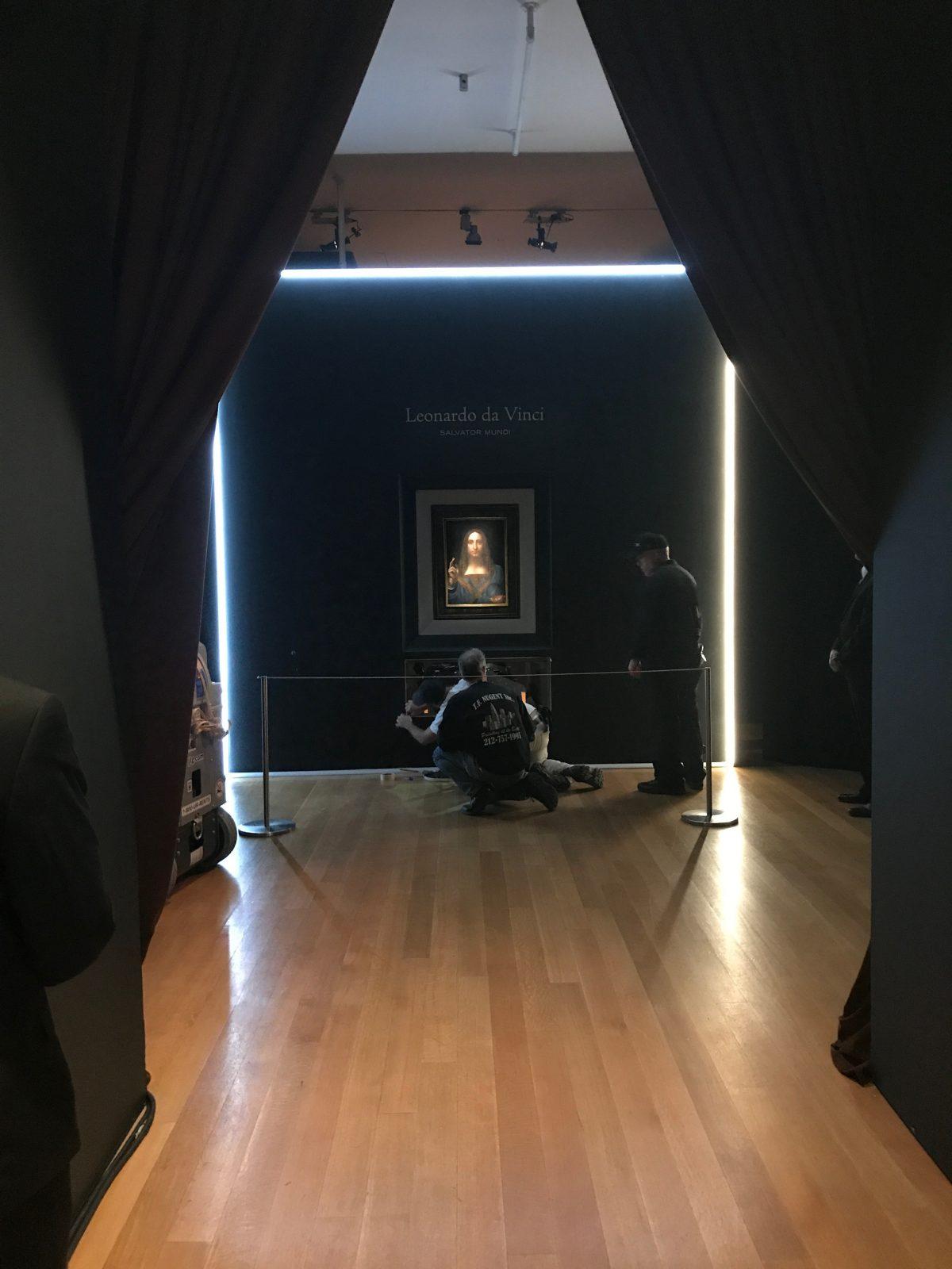 Christie's staff fix the installation of the "Salvator Mundi" painting by Leonardo da Vinci at Christie's in New York on Nov. 3, 2017. (Milene Fernandez/The Epoch Times)