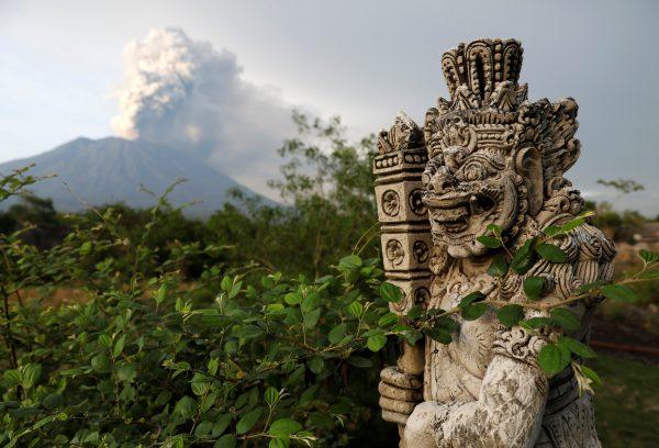 A statue on a bridge is seen as Mount Agung volcano erupts in the background near Kubu, Karangasem Regency, Bali, Indonesia, Nov. 28, 2017. (Reuters/Darren Whiteside)