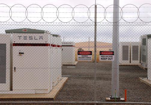 Warning signs adorn the fence surrounding the compound housing the Hornsdale Power Reserve, featuring the world's largest lithium ion battery made by Tesla, during the official launch near the South Australian town of Jamestown, in Australia, Dec. 1, 2017. (David Gray/Reuters)