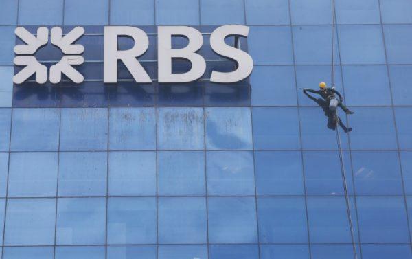 A worker cleans the glass exterior next to the logo of Royal Bank of Scotland bank on Sept. 8, 2017. (Reuters/Adnan Abidi)