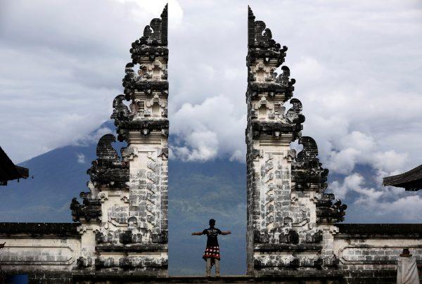 A Balinese man stands at the gate of Lempuyang temple looking towards Mount Agung volcano, in Karangasem Regency, Bali, Indonesia, Dec. 2, 2017. (Reuters/Darren Whiteside)