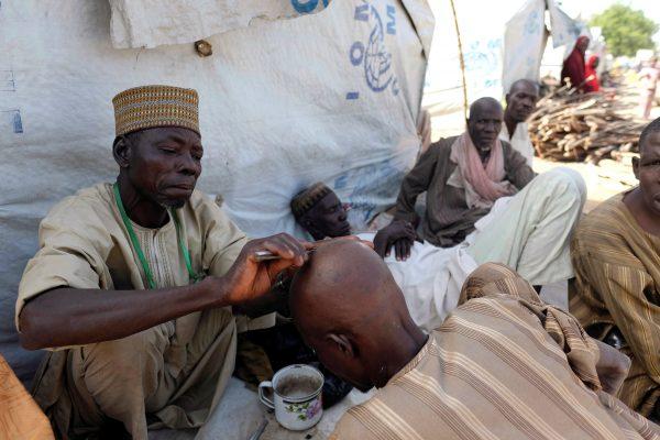 A barber shaves another man’s head in a camp for internally displaced people in Bama, in Borno state, Nigeria November 23, 2017. Picture taken November 23, 2017. (Reuters/Paul Carsten)