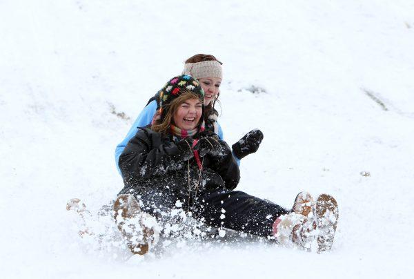 Hannah Craig (L) and Sophie Tapper, both 15, slide down a snow covered hill at Stormont estate in Belfast, Northern Ireland, on Dec. 17, 2010. (Peter Muhly/AFP/Getty Images)