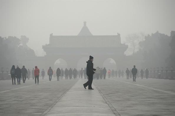 An elderly man walks in front of a group of people during heavy smog in Beijing on December 20, 2016. (Wang Zhao/AFP/Getty Images)