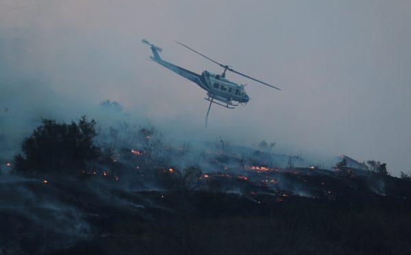 A firefighting helicopter makes a water drop on the Lilac Fire, a fast moving wildfire in Bonsall, California, Dec. 7, 2017. (Reuters/Mike Blake