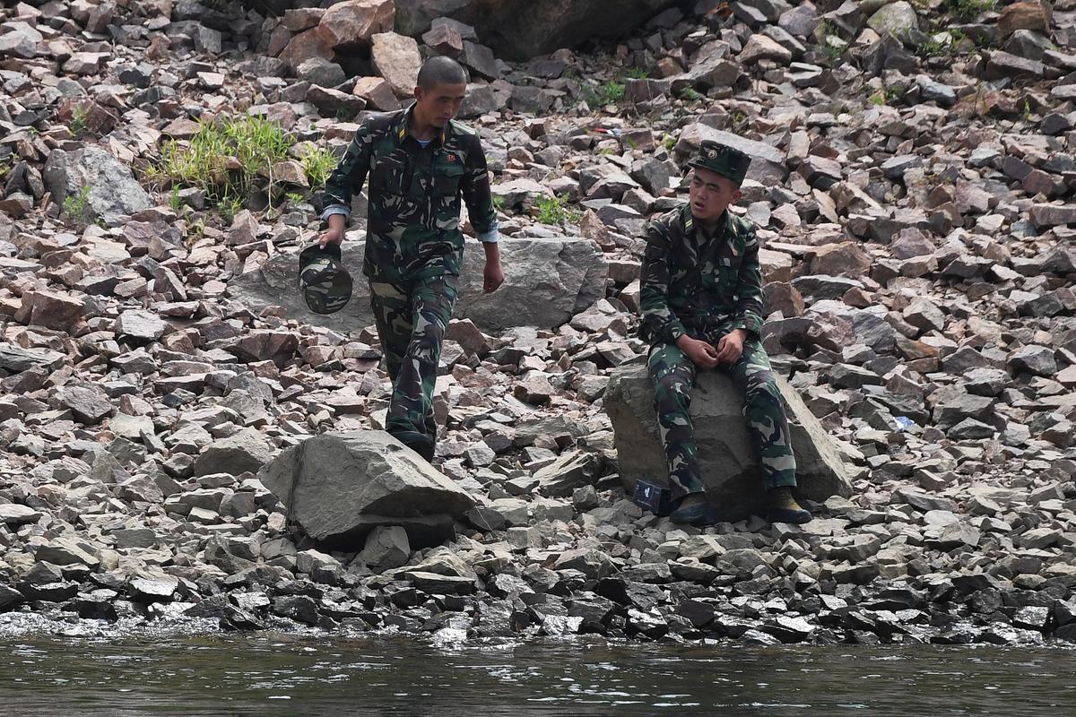 Two North Korean soldiers chat on the bank of the Yalu River near the North Korean town of Sinuiju, opposite the Chinese border city of Dandong, in China's northeast Liaoning province on Sept. 4, 2017. (GREG BAKER/AFP/Getty Images)