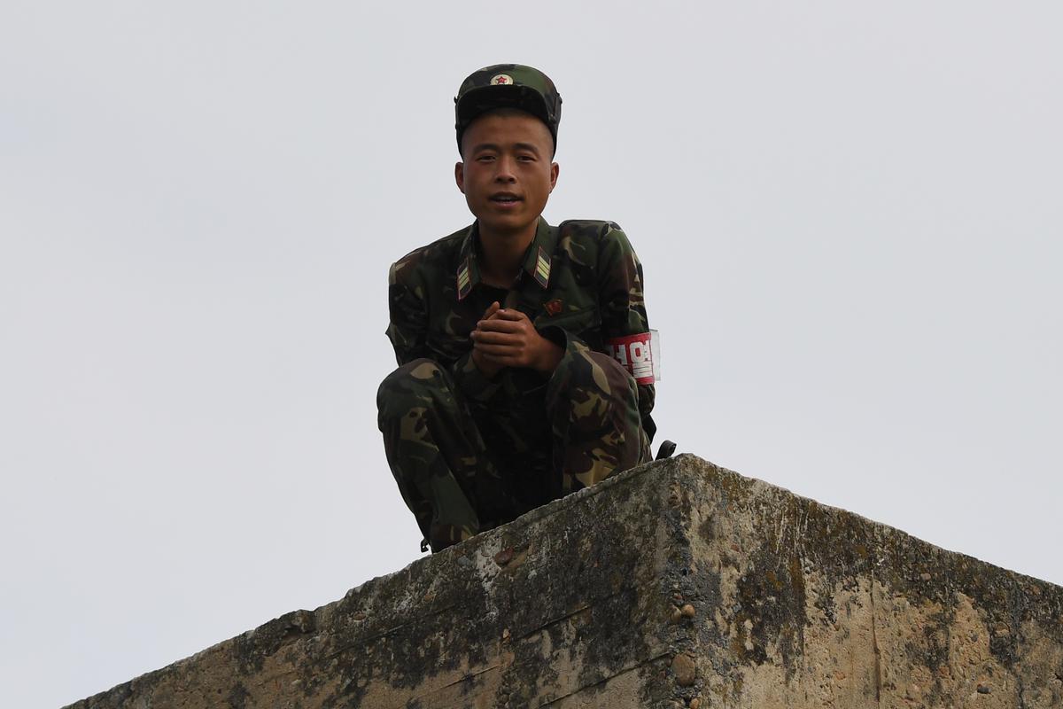A North Korean soldier chats with a Chinese boat driver as he crouches on a wall on the bank of the Yalu River near the North Korean town of Sinuiju, opposite the Chinese border city of Dandong, in China's northeast Liaoning province on Sept. 4, 2017. ( GREG BAKER/AFP/Getty Images)
