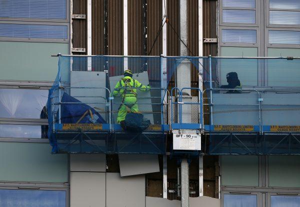 A worker removes cladding from Blashford Tower residential block on the Chalcots estate in north London, Britain, Nov.30, 2017. Picture taken Nov. 30, 2017. (Reuters/Hannah McKay)